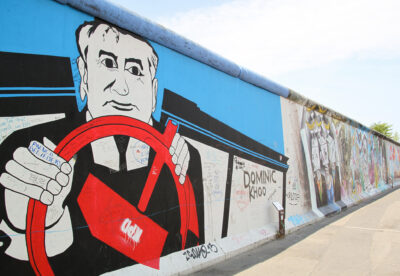 Kleurrijke muurschildering van een man met een rood stuur op de Berlijnse Muur, met levendige graffitikunst ernaast: een van de hoogtepunten en insidertips voor het ontdekken van verborgen pareltjes in Berlijn.