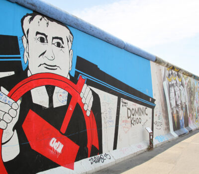 Kleurrijke muurschildering van een man met een rood stuur op de Berlijnse Muur, met levendige graffitikunst ernaast: een van de hoogtepunten en insidertips voor het ontdekken van verborgen pareltjes in Berlijn.