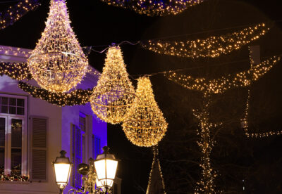 De Avondstraat is prachtig versierd met hangende gouden lampjes en verlichte bomen, ideaal voor een betoverende avondwandeling langs de levendige winkels in de stad.